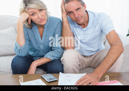 Anxious couple going over bills looking at camera Stock Photo