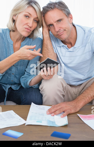 Anxious couple going over their debt looking at camera Stock Photo