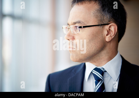 Portrait of thoughtful businessman looking through window Stock Photo