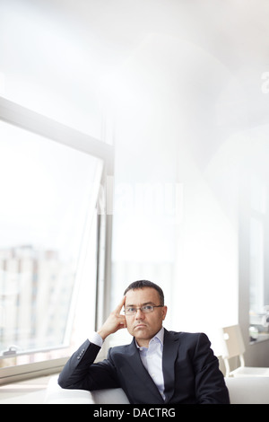 Copy-spaced vertical portrait of a contemplative businessman thinking over serious matters Stock Photo