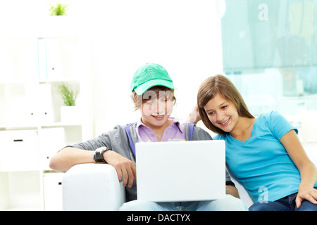 Teen friends hanging out together at home with a laptop Stock Photo
