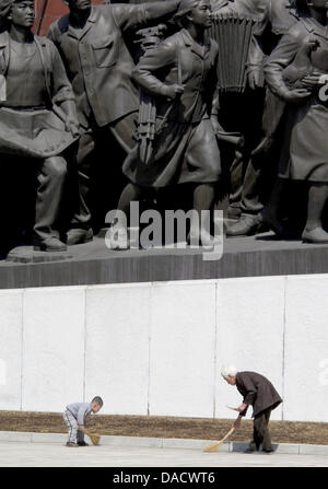 FILE - An archive picture dated 03 April 2011 shows a boy and an old woman cleaning in front of a monument at the Mangyongdae Hill in Pyongyang, Republic of Korea.  After the death of North Korean leader Kim Jong-il, Pyongyang described his son Kim Jong-un as the 'great successor' and urged North Koreans to unite behind him, North Korea's state-run news agency, KCNA, reported on 19 Stock Photo