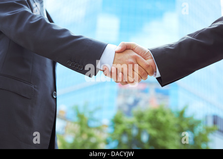 Business associates shaking hands beginning their partnership Stock Photo