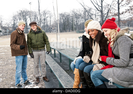 Two young men looking at three pretty women in winter park Stock Photo