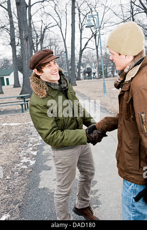 Two young men meeting in winter park shaking hands Stock Photo