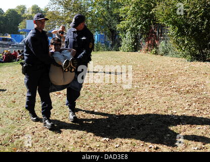 An female opponent of the controversial railway construction project Stuttgart 21 is removed by the police after attending a sitting blockade against the preparations for the laying of pipes of the groundater management at the Palace garden in Stuttgart, Germany, 04 October 2011. On the left, the technical building for the groundwater management is seen. The police removed the sitt Stock Photo