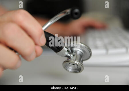 (dpa-file) - A file picture dated 25 May 2010 shows a doctor holding a stethoscope in his hands while sitting at the computer in a medical office in Deizisau, Germany. Germany's doctors suggest that varying doctors from different places shall treat patients in rural areas to cover the lack of doctors  in the countryside. Photo: Marijan Murat Stock Photo