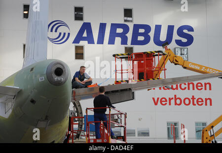 FILE - An archive picture dated 06 February 2009 shows employees standing next to an Airbus in the final assembly hangar at the Airbus plant in Hamburg-Finkenwerder, Germany. In the trade conflict at aircraft manufacturer Airbus both parties endeavour to reach a compromise. On Wednesday, 05 October 2011, representatives of Airbus, the trade union IG Metall, and the works committee  Stock Photo