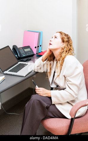 Businesswoman worried in office workstation looking up Stock Photo