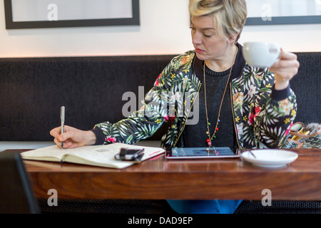 Woman writing in notepad in cafe Stock Photo