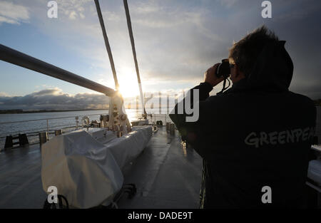 A crew member of the new Greenpeace flagship 'Rainbow Warrior III' stands on the front deck during its maiden voyage on the River Elbe in the port of Hamburg, Germany, 20 October 2011. The 58 meter long sailing ship arrived in the port of Hamburg this afternoon. Photo: CHRISTIAN CHARISIUS Stock Photo
