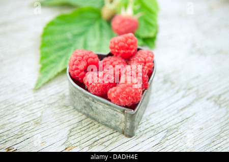 Raspberries in heart on old wooden table Stock Photo