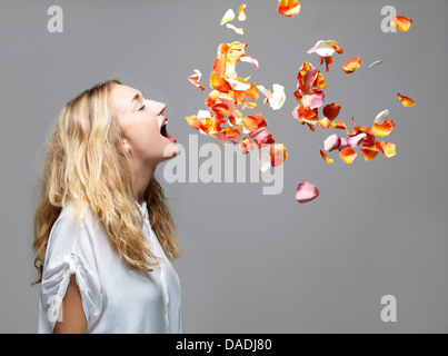 Young woman with mouth open an petals floating in mid air Stock Photo