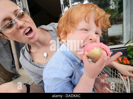 Mother with toddler eating pink covered cake Stock Photo