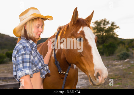 USA, Texas, Young woman standing with horse Stock Photo