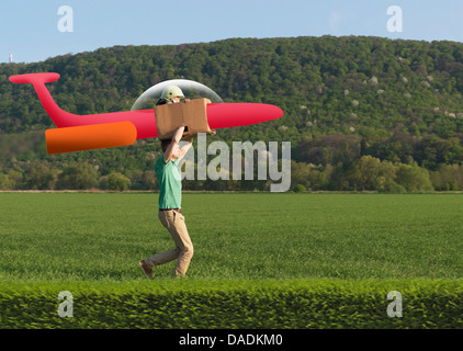 Man running with child in model airplane across field Stock Photo