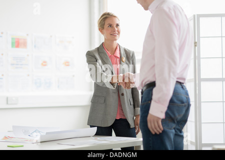 Businesswoman shaking hands with man in office Stock Photo