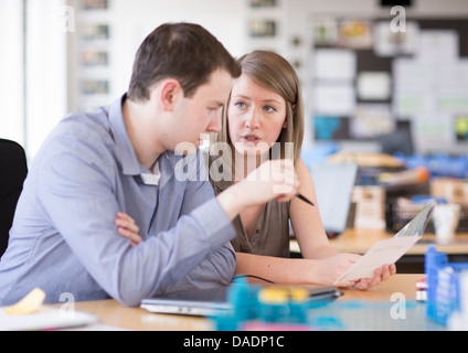 Young man and woman working on laptop in creative office Stock Photo