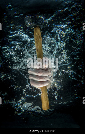 Male hand gripping hammer beneath water Stock Photo