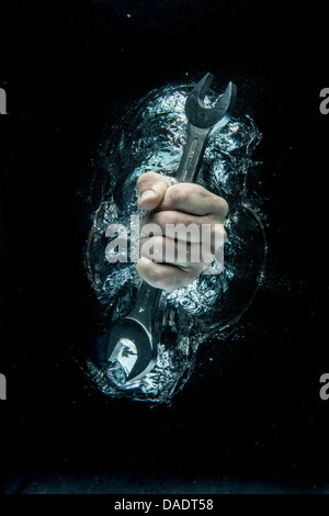 Male hand gripping wrench beneath water Stock Photo