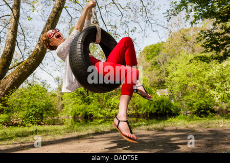 Young woman having fun on tire swing Stock Photo