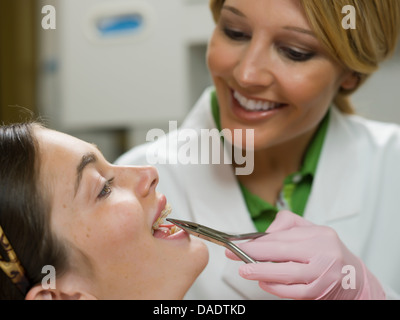 Dentist using dental pliers on young woman's braces Stock Photo