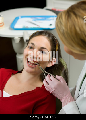 Dentist using dental pliers on young woman's braces Stock Photo