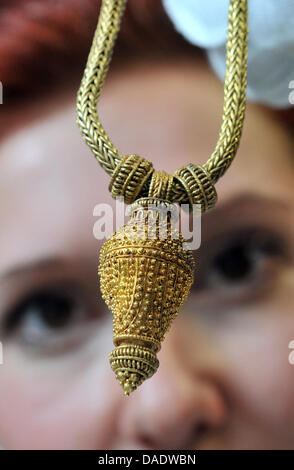 A young woman looks at an around 2000 year old piece of gold jewelry of a Germanic priestess at the State Office for Monument Conservation in Halle (Saale), Germany, 11 October 2011. Archaeologists discovered the treasure in an urn grave during excavations of Profen strip mine in 2007. From 9 December, the treasure will be displayed for the first time during the state exhibition 'P Stock Photo