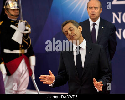President of France Nicolas Sarkozy greets German Chancellor Angela Merkel (not pictured) in Cannes, France, 02 November 2011. France's Foreign Minister Alain Juppe stands behind them. Merkel and Sarkozy as well as the heads of the EU, the ECB and IWF are meeting for a special summit to discuss the newest developments of the crisis in Greece. Then on 03 and 04 November 2011, the he Stock Photo
