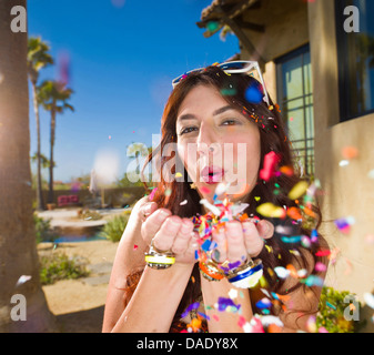 Young woman blowing confetti, portrait Stock Photo