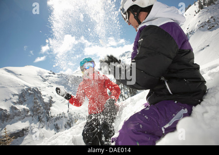 Mid adult man and young woman in skiwear having snowball fight Stock Photo
