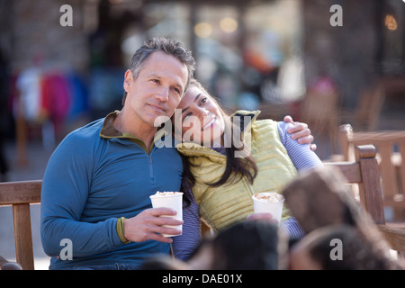 Couple sitting and enjoying warm drinks outside Stock Photo