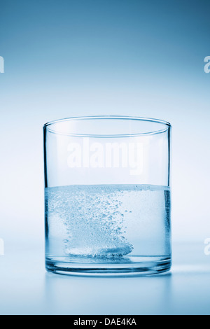 Tablet fizzing in glass of water Stock Photo