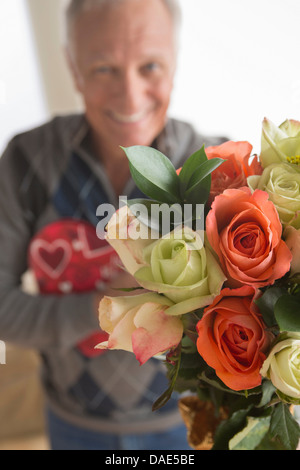 Senior man holding bunch of flowers and chocolates Stock Photo