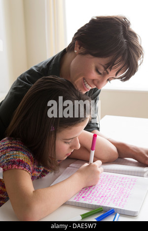 Mother watching daughter writing Stock Photo