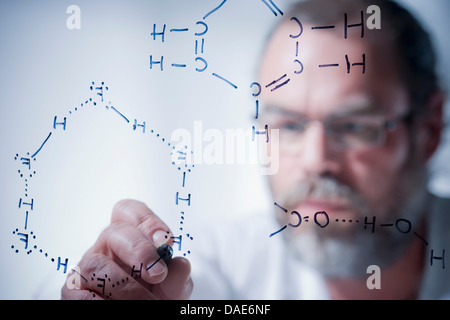 Scientist writing scientific symbols on glass Stock Photo