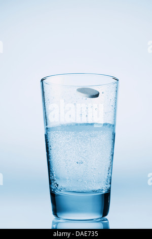 Tablet falling in glass of water Stock Photo