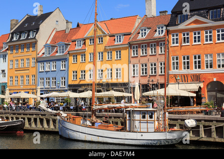 Old wooden boat on canal with cafes and colourful buildings on 17th century waterfront in Nyhavn harbour Copenhagen Denmark Stock Photo