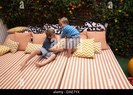 Two boys playing on outdoor furniture with cushions Stock Photo