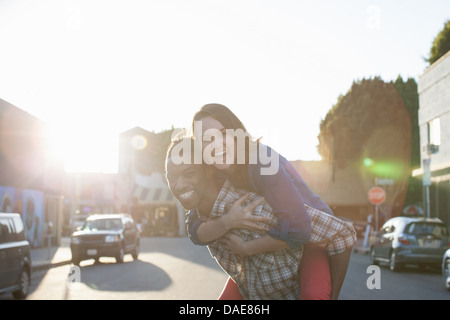 Young man giving woman piggy back Stock Photo