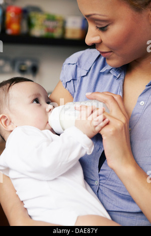Mother feeding baby girl bottle of milk