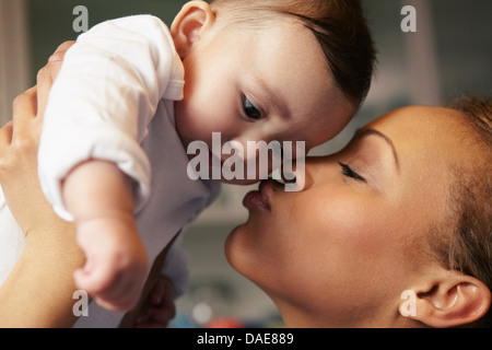 Mother kissing baby girl's cheek Stock Photo