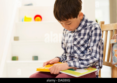 Young boy sitting on chair studying game Stock Photo