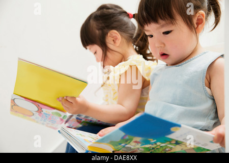 Two young sisters looking at picture books Stock Photo