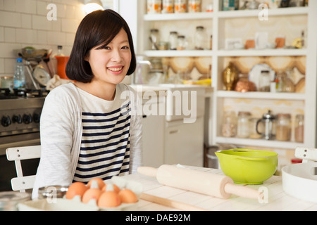 Portrait of young woman at kitchen table with baking ingredients Stock Photo