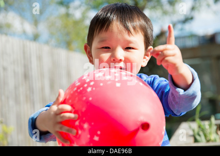 Male toddler in garden with red balloon Stock Photo