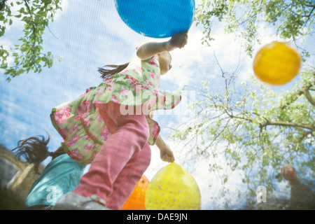 Young girls bouncing on garden trampoline with balloons Stock Photo