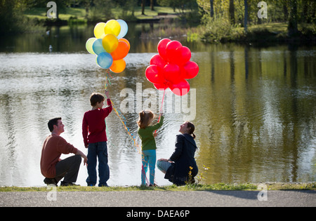 Family in front of lake with bunches of balloons Stock Photo