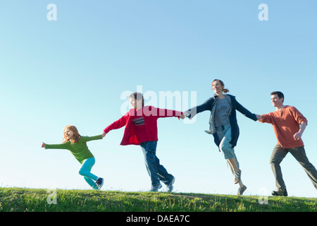 Parents and two children running and holding hands Stock Photo