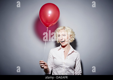 Studio portrait of mature woman with red balloon Stock Photo
